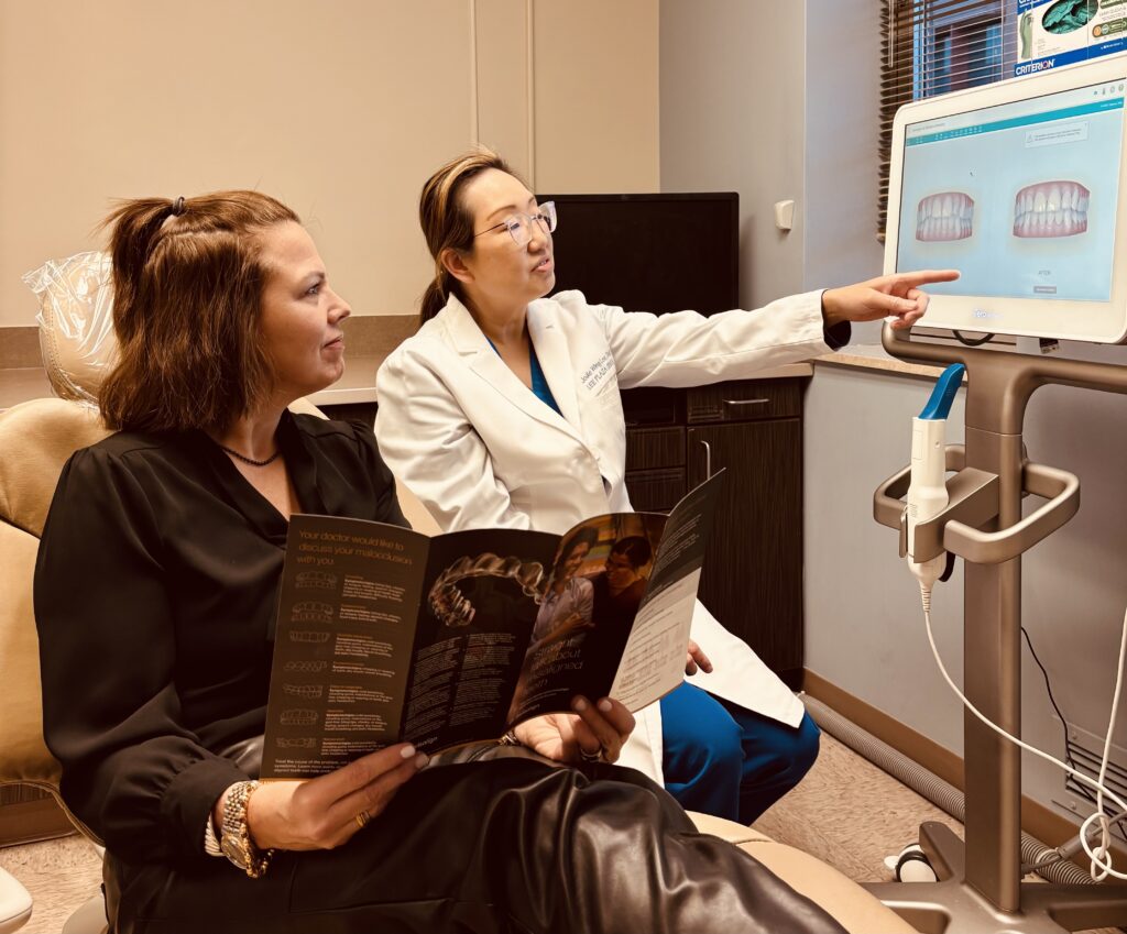 Adult patient reviewing Invisalign treatment options with a dentist using a digital smile simulation during a consultation.